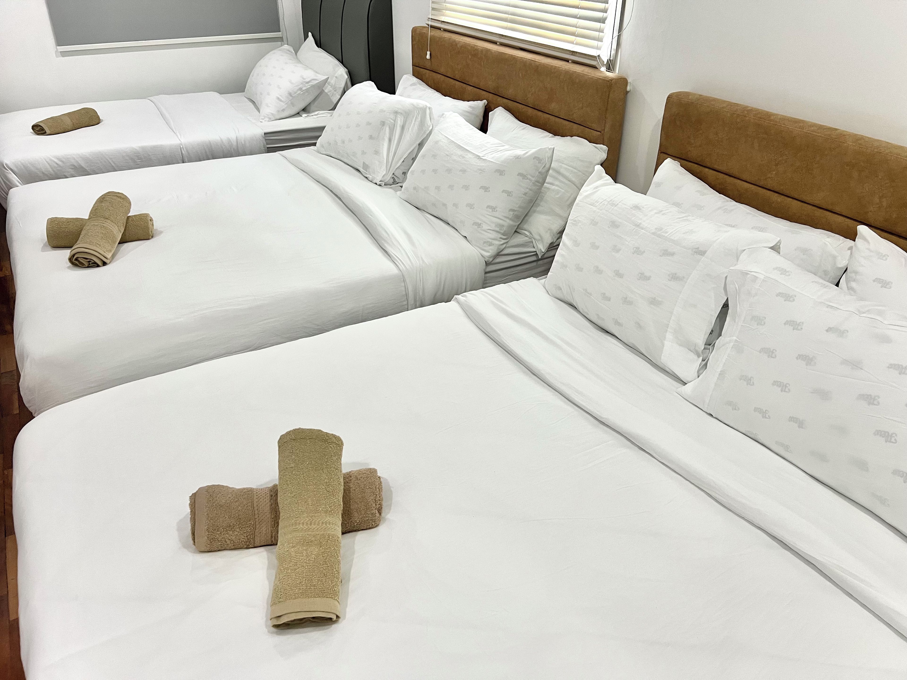 A hotel room with two beds, each with white linens and pillows, and a brown headboard.