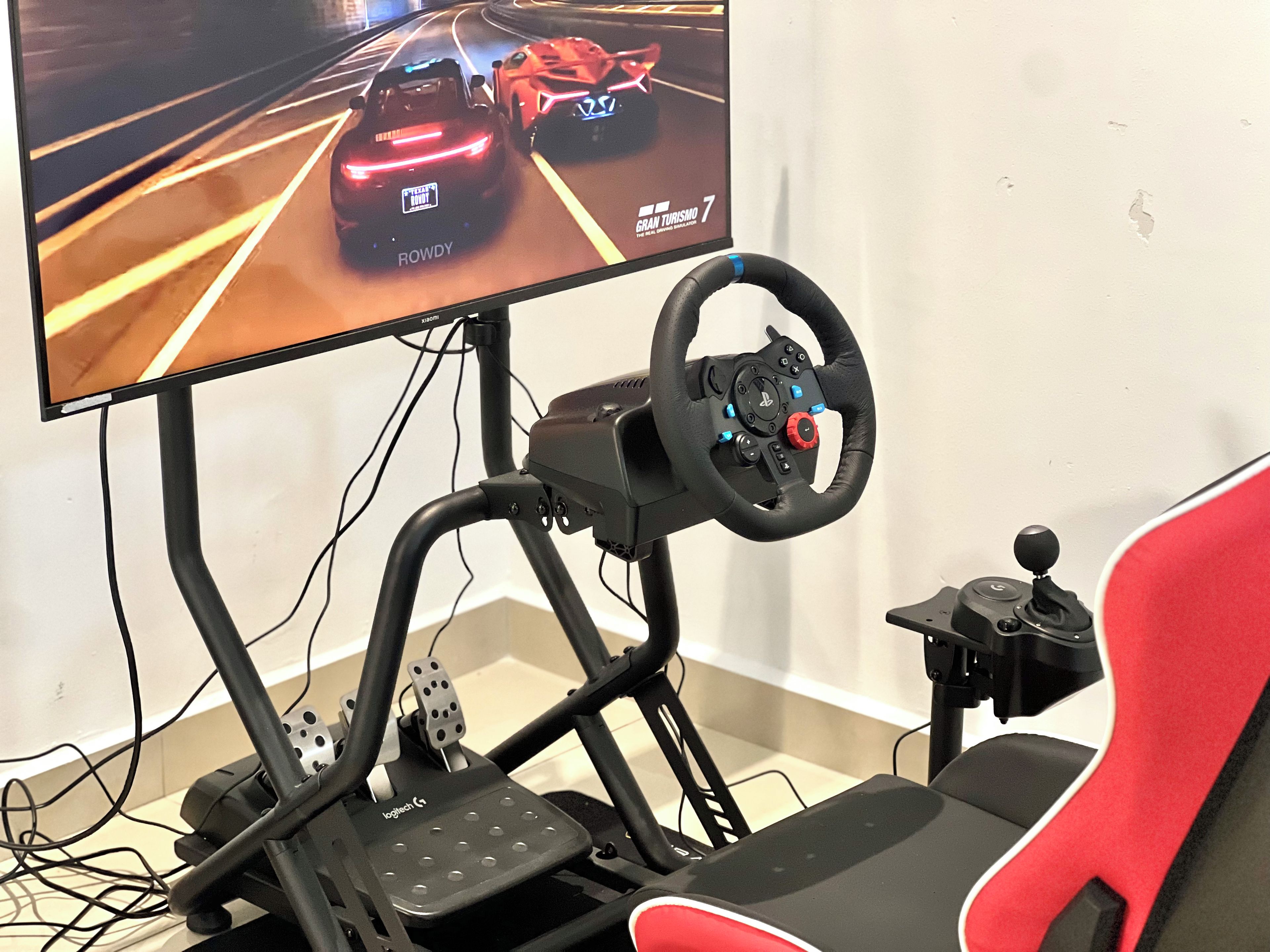 A racing simulator setup with a steering wheel, pedals, and a monitor displaying a racing game.