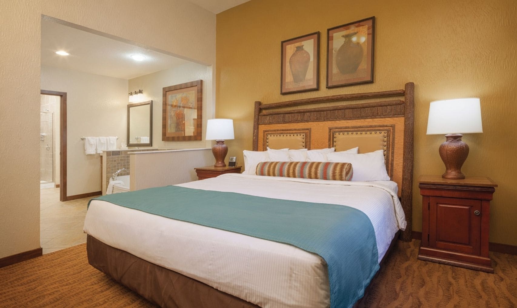 A hotel room with a large bed, a bathroom with a shower, and a mirror.