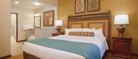 Una habitación de hotel con una cama grande, un baño con ducha y un espejo.