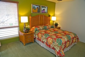 Quarto com cama, duas mesas de cabeceira, duas luminárias, janela com persianas e dois quadros na parede.