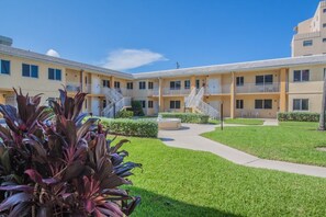 Ein mehrstöckiges Motel mit Innenhof, Außenbereich zum Sitzen und einer Treppe zu den oberen Stockwerken.