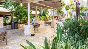 Un patio al aire libre con suelo de piedra, mobiliario exterior y varias plantas.