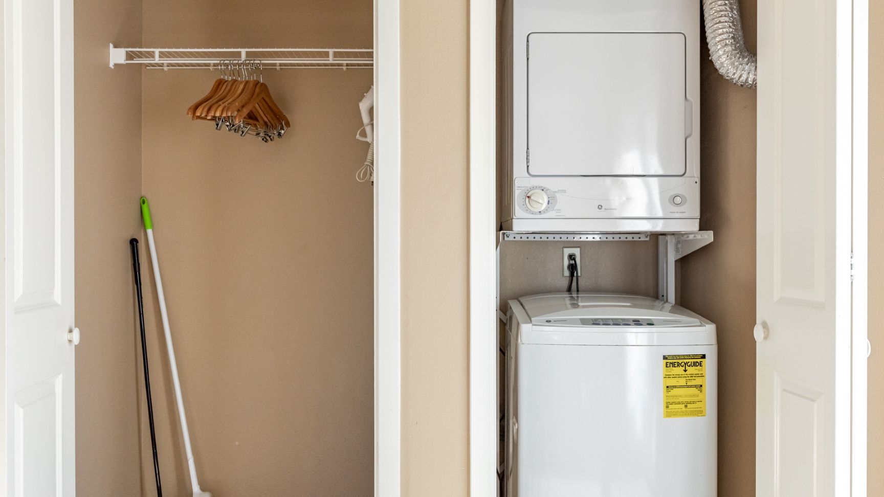 A laundry area with a washing machine, a drying rack, and a mop.