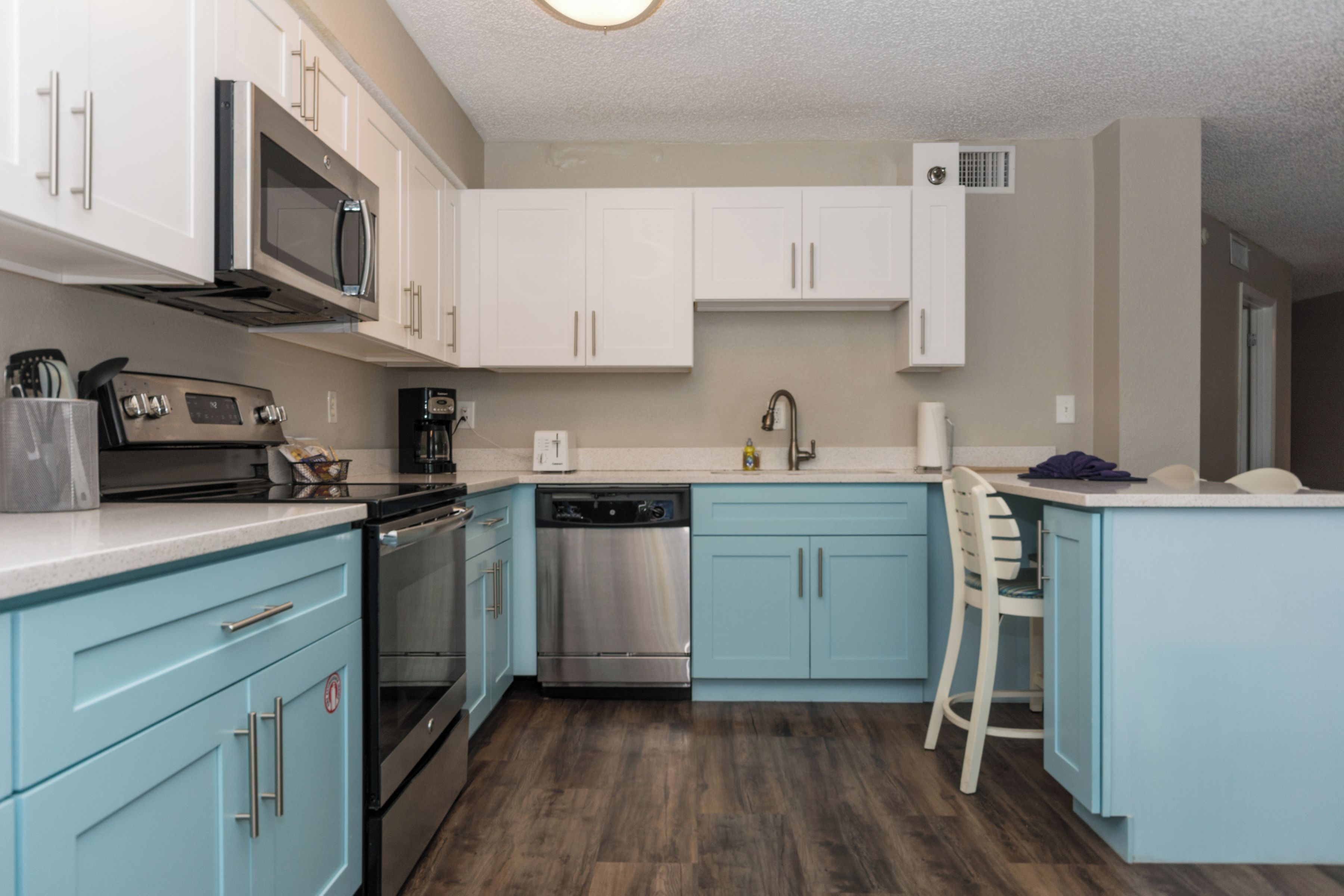 A modern kitchen with white cabinets, stainless steel appliances, and a blue countertop.
