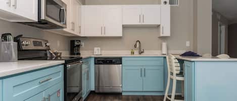 A modern kitchen with white cabinets, stainless steel appliances, and a blue countertop.