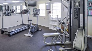 Une salle de sport équipée de tapis de course, de vélos d’appartement et d’appareils de musculation.