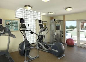 A gym with treadmills, elliptical machines, and a red exercise ball.