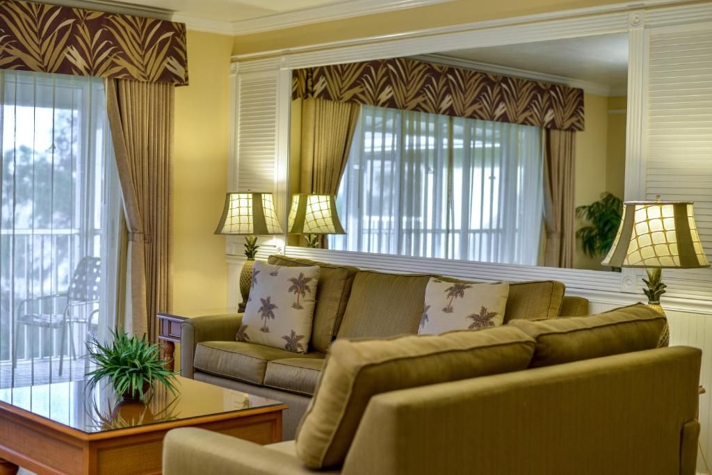 A living room with a sofa, two lamps, a coffee table, and a large window with curtains.