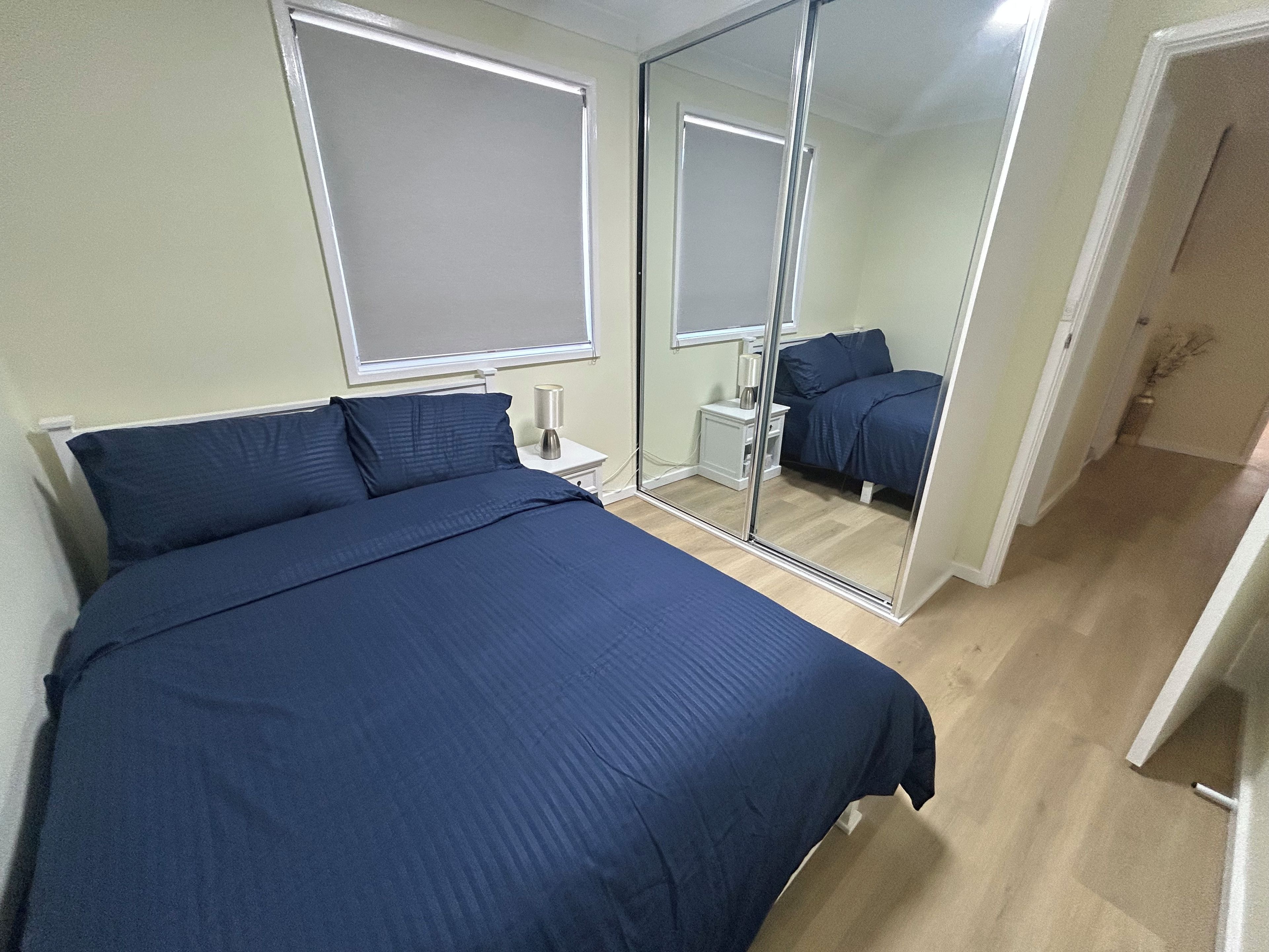 A bedroom with a bed, a nightstand, a lamp, and a mirror.
