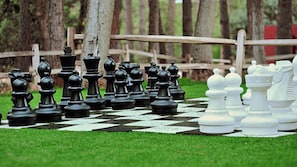 A chessboard with chess pieces set up on a grassy area with trees in the background. - Payson | Secluded Cabin Retreat | Pool + Hot Tub (Payson)
