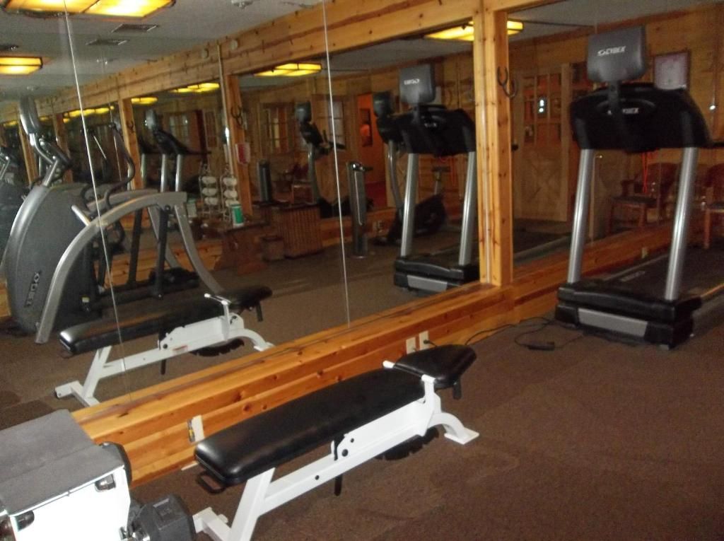 A gym with exercise equipment, including treadmills and a bench.