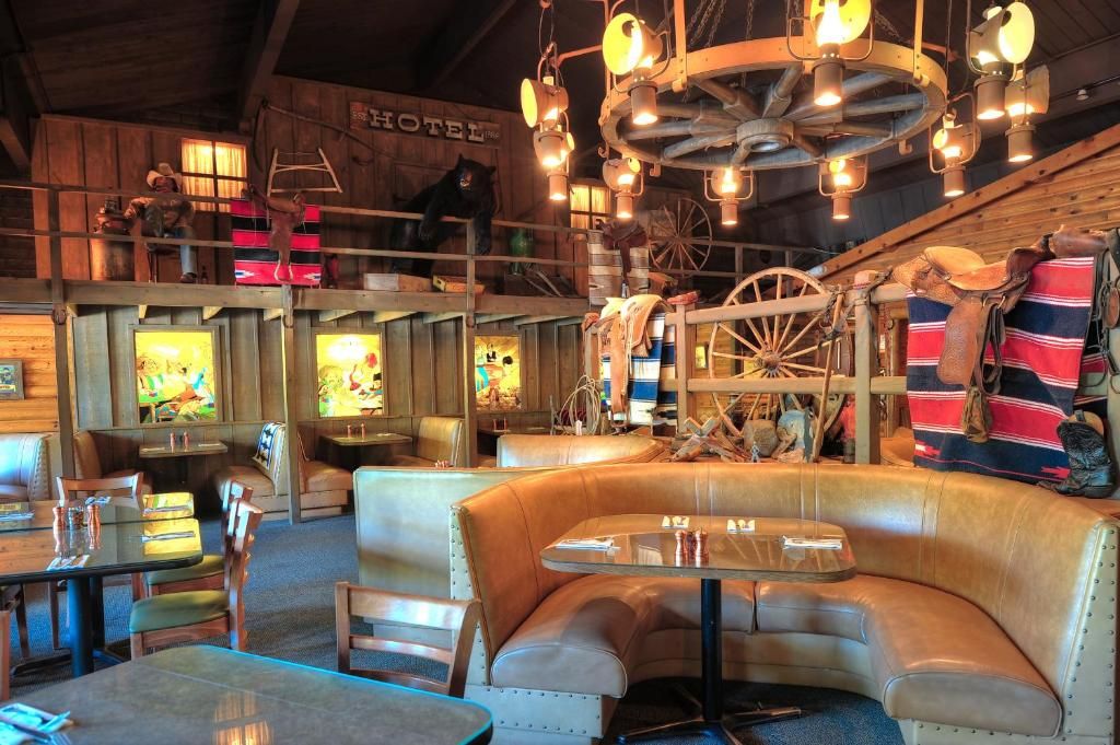 A rustic interior with leather seating, a wooden ceiling, and a chandelier.