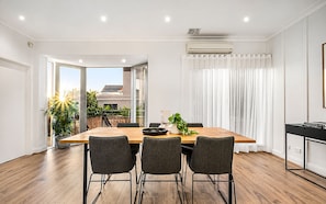 A modern dining area with a wooden table, four chairs, and a potted plant. - Brighton Coastal Townhouse with 2 Private Parking (Brighton)