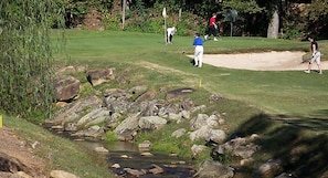 Ein Golfplatz mit Bach, Felsen und Sandbunkern.