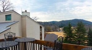 A deck with outdoor seating and a view of a river and mountains. - Lake Lure | Family Mountain Retreat | Pool + Tennis | 2BR (Lake Lure)