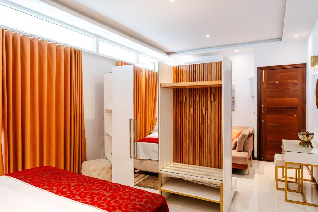 A hotel room with a bed, a seating area, a wardrobe, and a door.