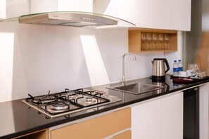 A modern kitchen with a gas stove, stainless steel sink, and a glass-fronted range hood.