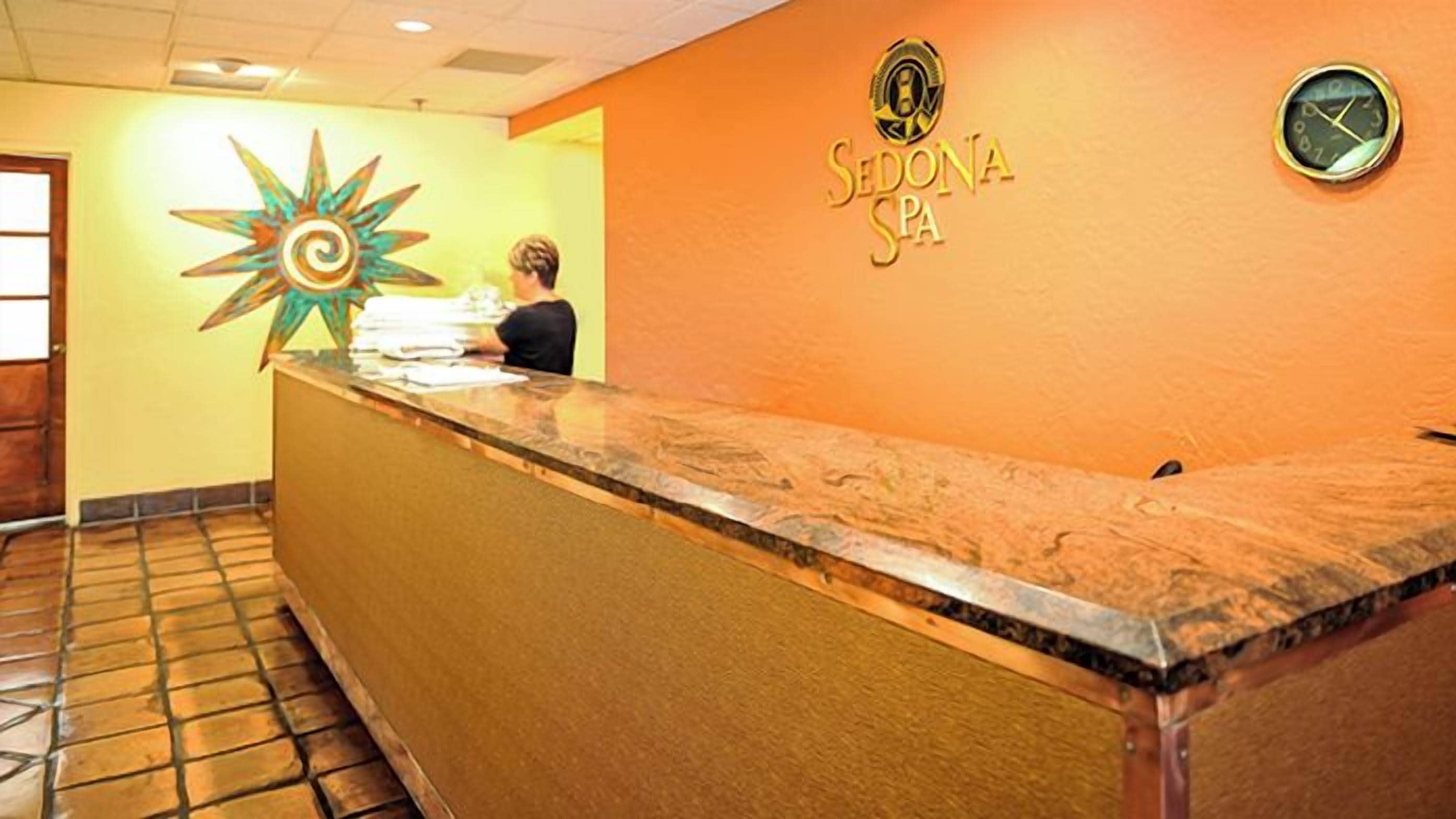 A reception desk with a clock and a logo for 'Sedona Spa' on the wall.