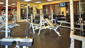 Un gimnasio con varios equipos de ejercicio, incluyendo máquinas de pesas y mancuernas.