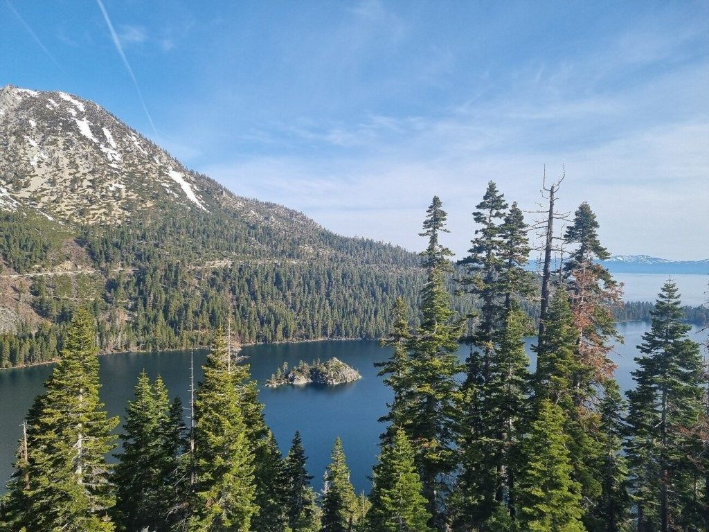 Un paisaje montañoso con un lago, un bosque denso y un cielo despejado.