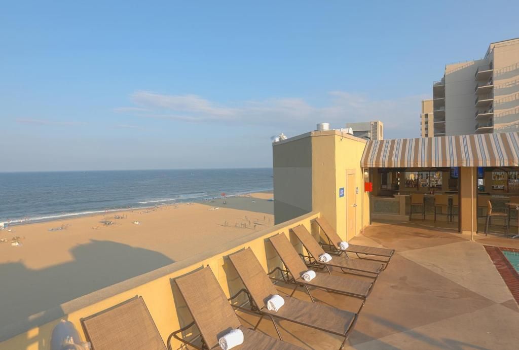 Een hotel aan het strand met een zwembad, ligbedden en uitzicht op zee.