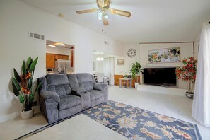 A living room with a gray sofa, a flat-screen TV, a ceiling fan, and a large painting on the wall. - 2 Mi to Downtown: Cozy Hubbard Home (Garland)