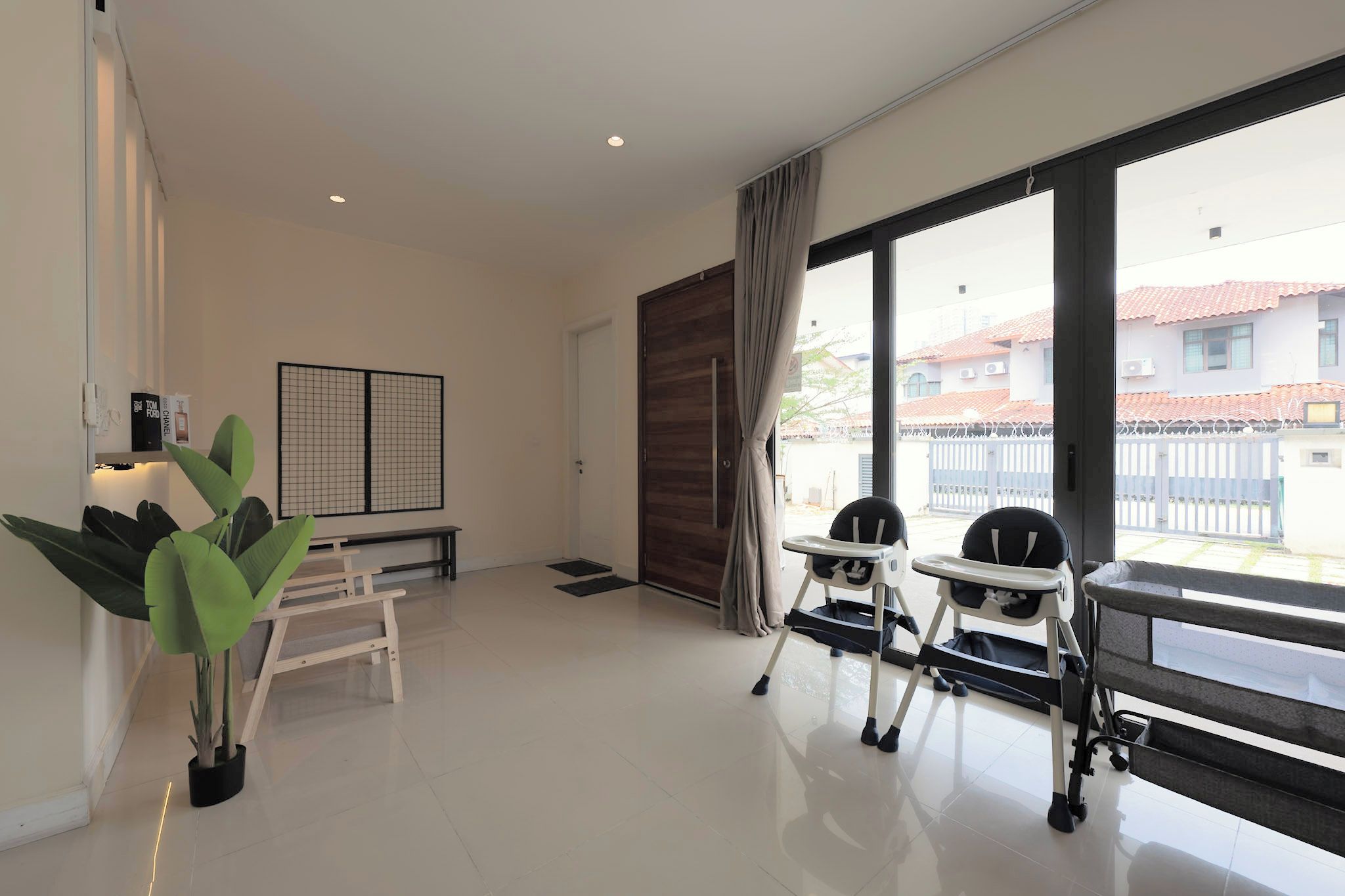 A modern living room with a large window, a sliding door, a small table, and a potted plant.