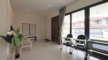 A modern living room with a large window, a sliding door, a small table, and a potted plant.