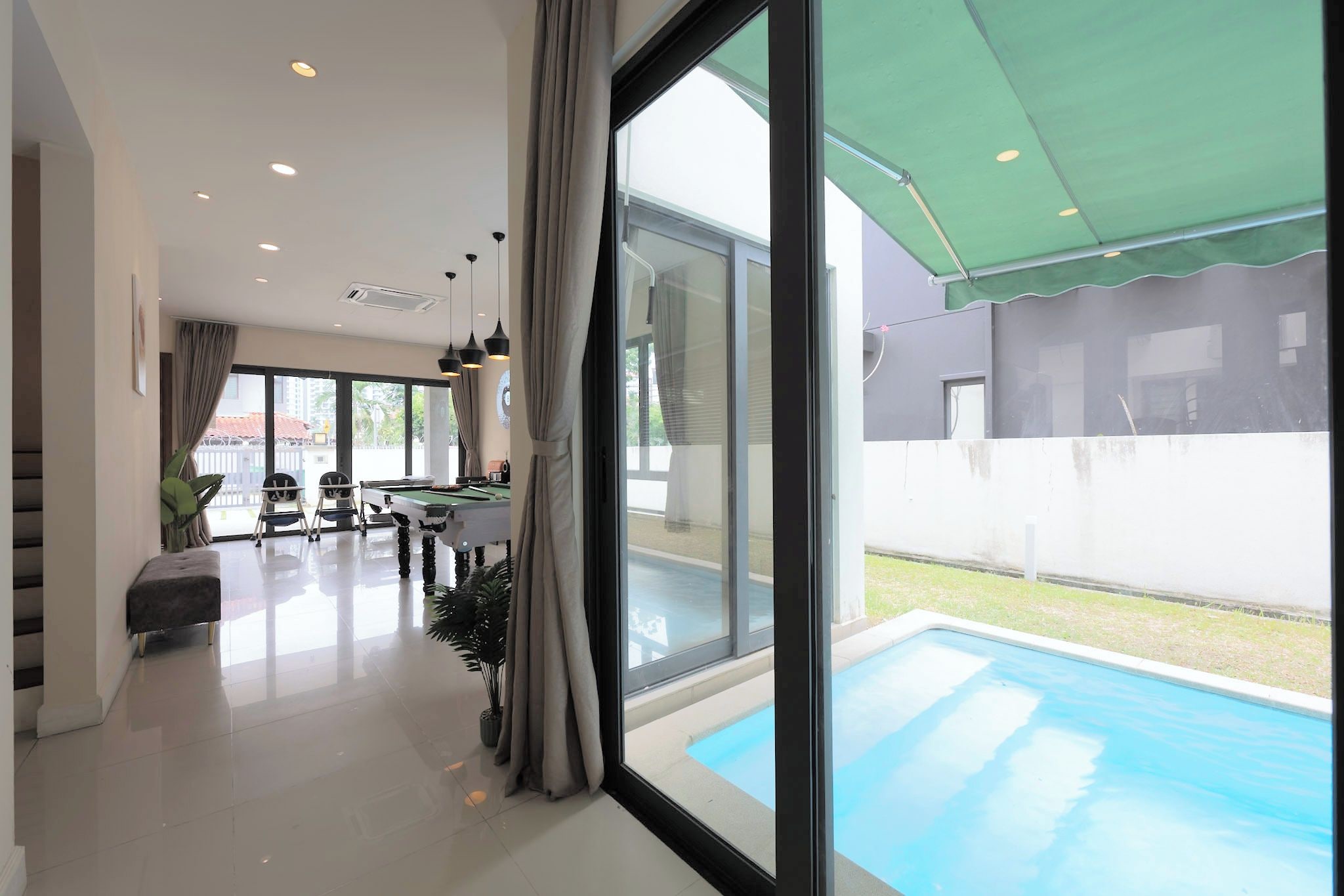 Una sala de estar moderna con piscina, ventanas amplias y comedor.