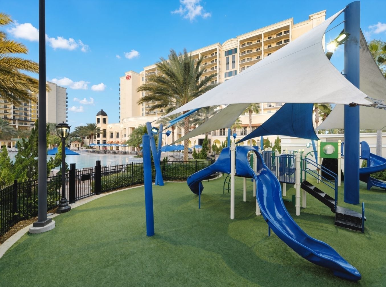 A playground with slides and a pool in the background.