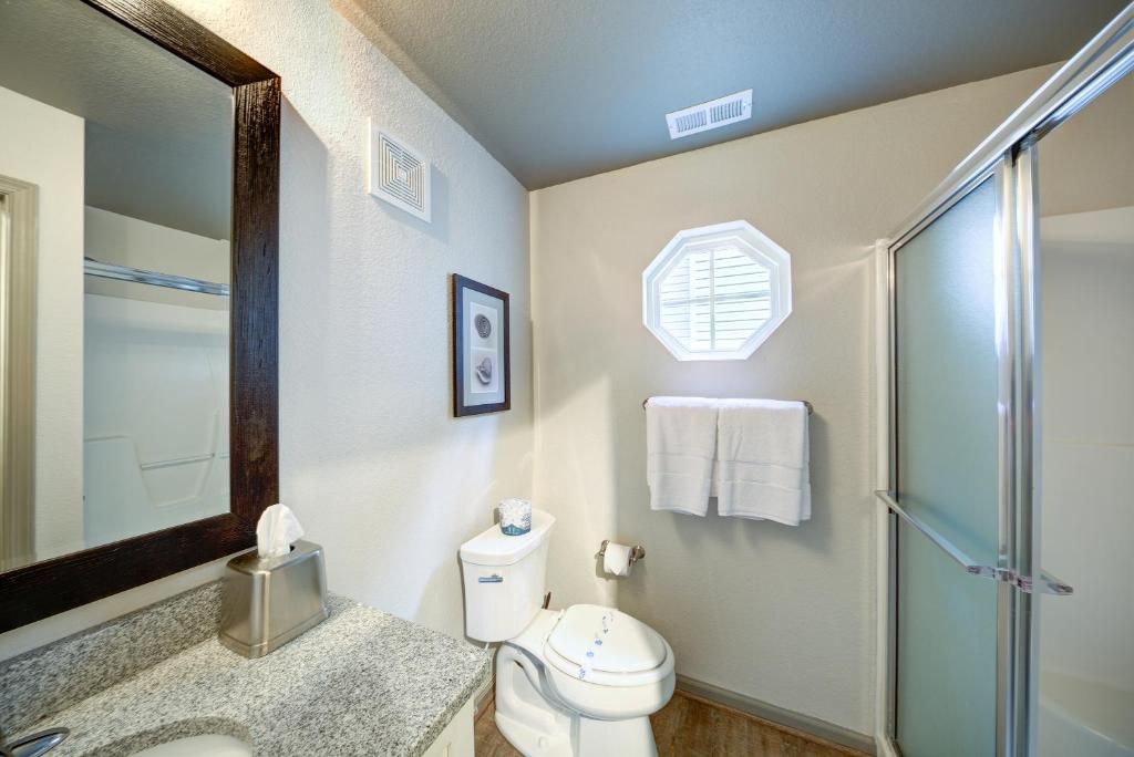 A bathroom with a large mirror, a toilet, a sink, a towel rack, and a shower.