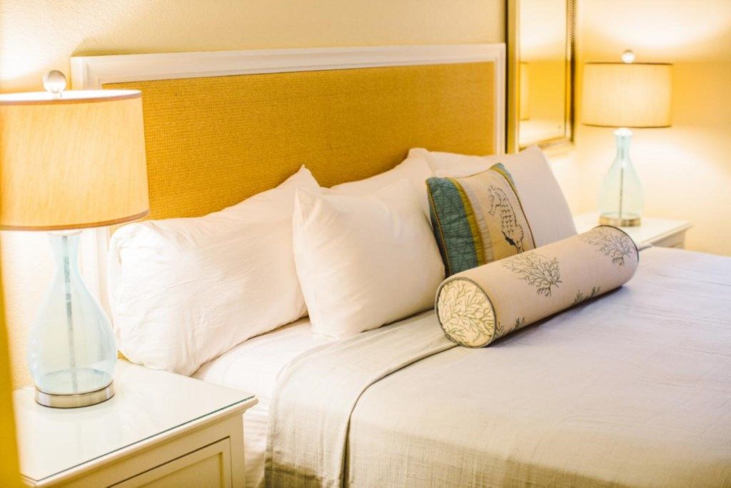 Une chambre d’hôtel avec un lit, des oreillers, une table de chevet et une lampe.