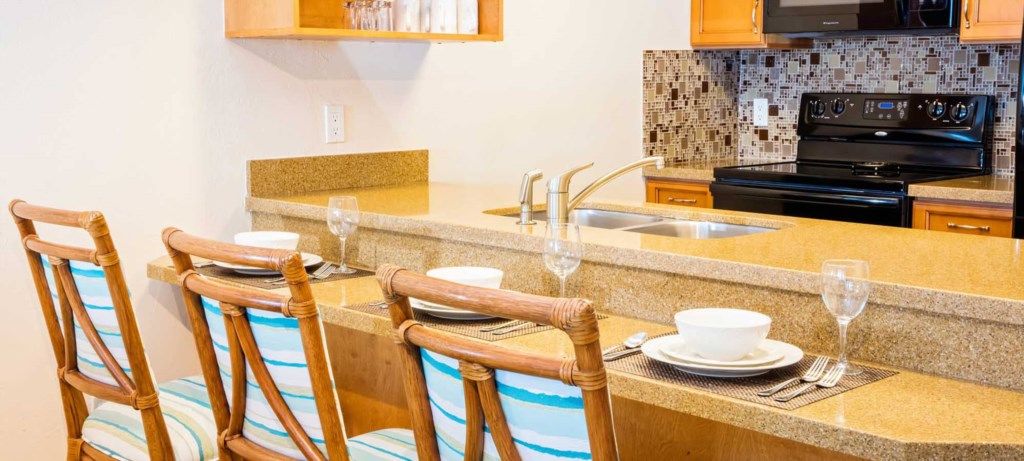 A kitchen with a granite countertop, a black stove, and a tiled backsplash.