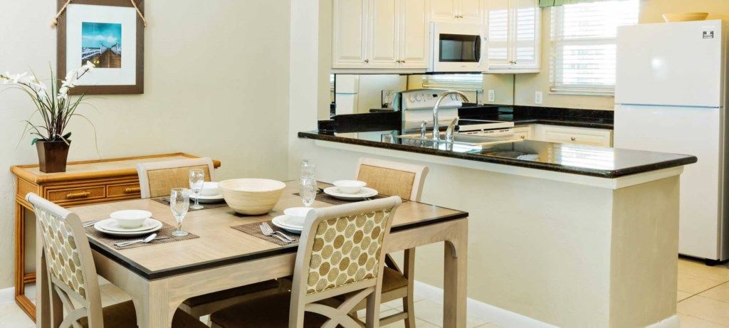 A modern kitchen with white cabinets, a black countertop, and a white refrigerator.