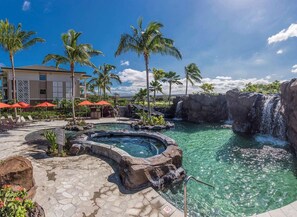 Un complexe hôtelier doté d’une piscine, de palmiers et d’une cascade.