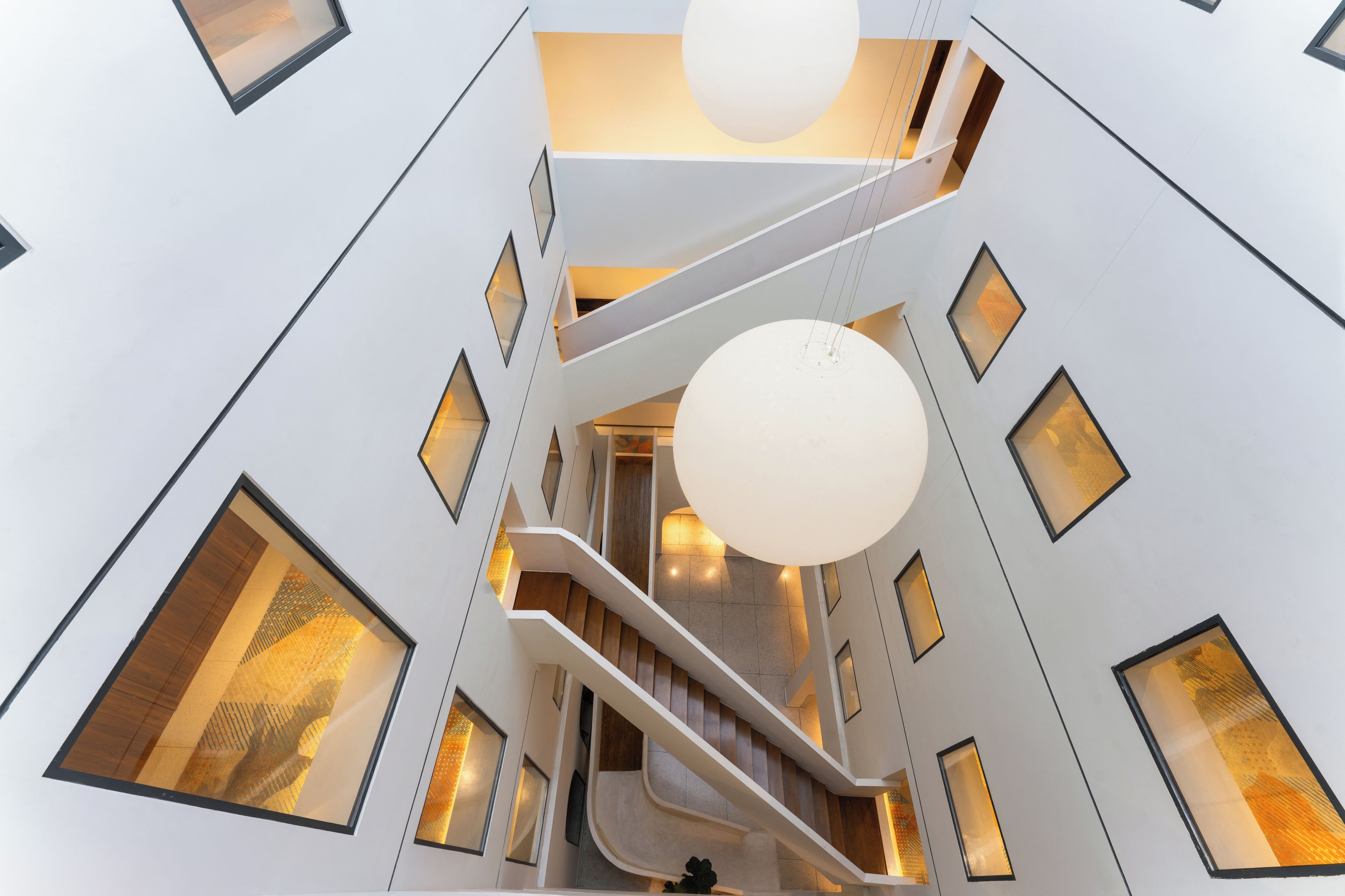 A modern interior with a central staircase, multiple levels, and large windows.
