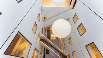 A modern interior with a central staircase, multiple levels, and large windows.