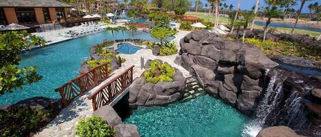 A resort with a large pool, a waterfall, and palm trees.