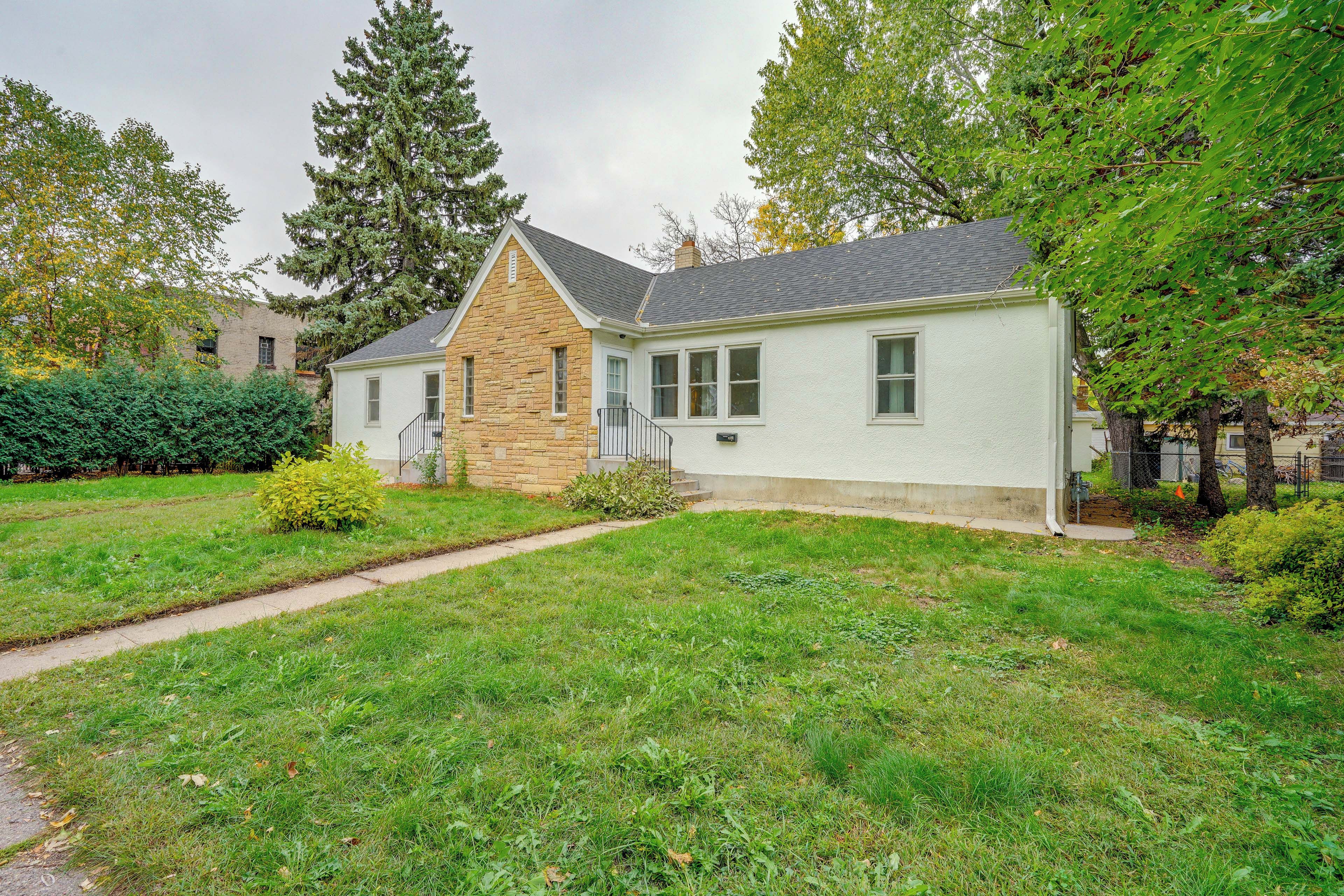 A two-story house with a stone facade, a front porch, and a well-maintained lawn.