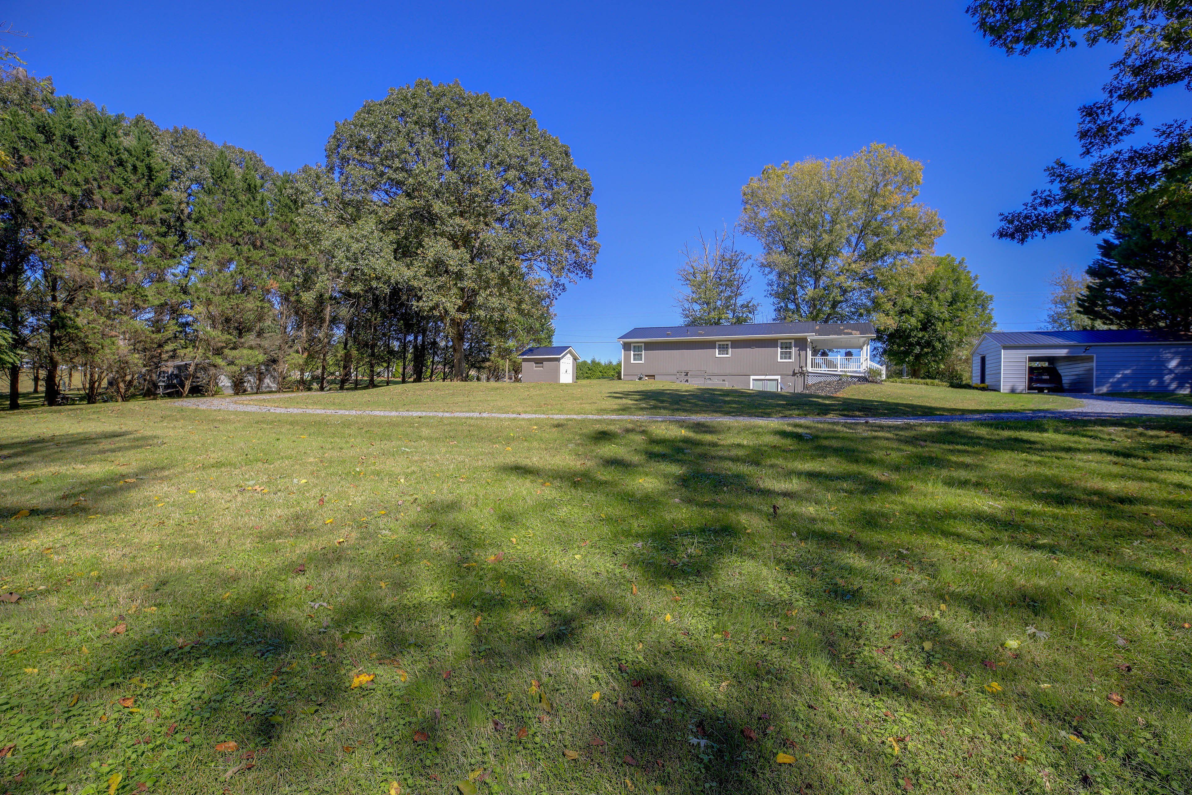 A residential property with a large lawn, a house with a porch, and a garage.