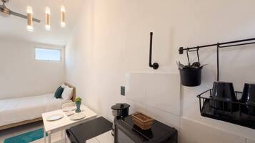 A compact kitchenette with a microwave, a small dining table, and a bed in the adjacent room.