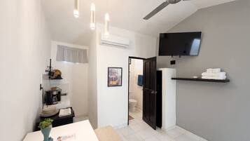 A modern bathroom with a ceiling fan, a mounted TV, and a towel rack.