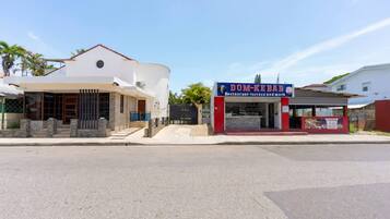 A street view with a modern two-story building and a small food kiosk.