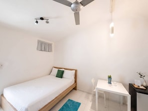 A bedroom with a bed, a desk, a chair, a ceiling fan, and a window with a curtain. - Central Studio in Sosua with Breakfast included! (Sosúa)