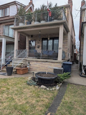 A two-story residential building with a balcony, a front door, and a visible address number. - King Size In-Suite Basement (Toronto)