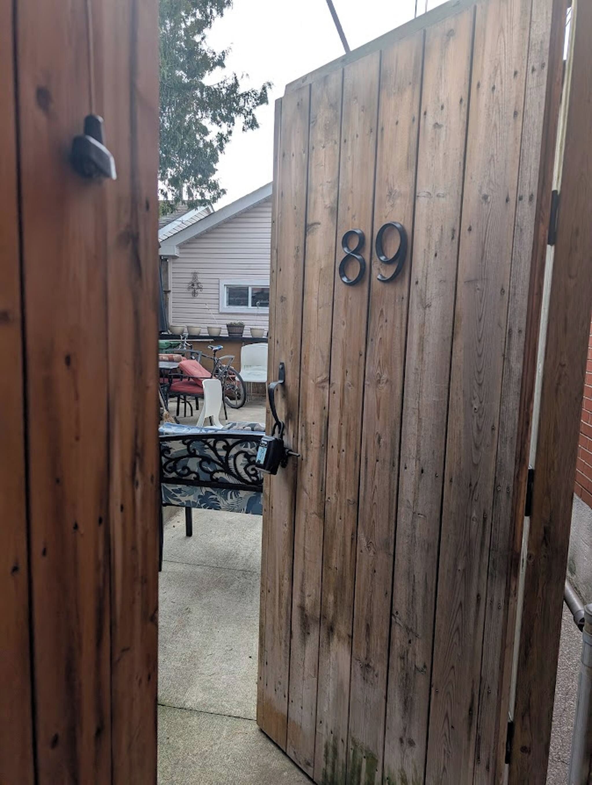 A wooden gate with the number 89, leading to an outdoor area with a patio table and chairs.
