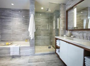 Uma casa de banho moderna com chuveiro em cabine de vidro, banheira e toucador com espelho.