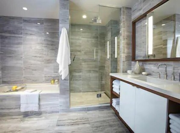 A modern bathroom with a glass-enclosed shower, a bathtub, and a vanity with a mirror.