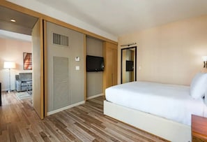 Quarto de hotel com cama, televisão, escrivaninha e cadeira.